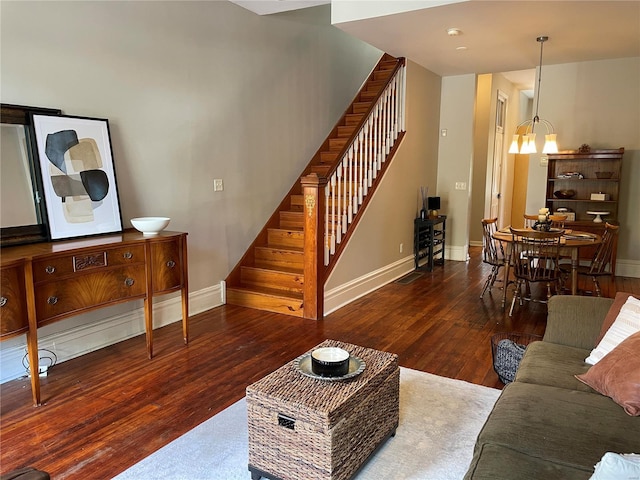 living room with an inviting chandelier and dark wood-type flooring