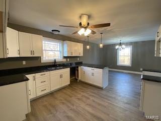 kitchen featuring a healthy amount of sunlight, ceiling fan with notable chandelier, wood-type flooring, and white cabinets