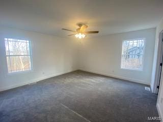 unfurnished room with dark colored carpet, ceiling fan, and plenty of natural light