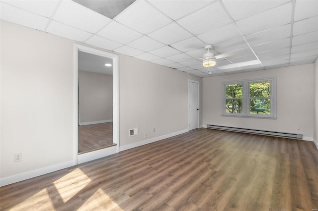 spare room with ceiling fan, a drop ceiling, dark hardwood / wood-style floors, and a baseboard heating unit