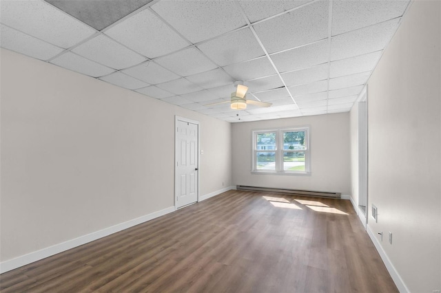 unfurnished room with ceiling fan, a baseboard radiator, a drop ceiling, and wood-type flooring