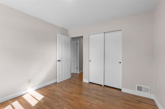 unfurnished bedroom with dark wood-type flooring and a closet