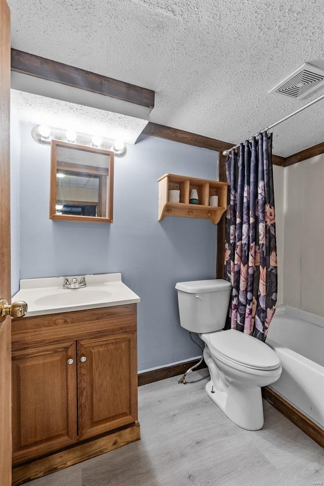 full bathroom with shower / bath combination with curtain, vanity, wood-type flooring, a textured ceiling, and toilet