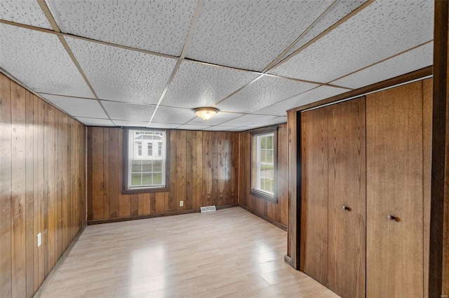 interior space with wooden walls, light hardwood / wood-style flooring, and a paneled ceiling