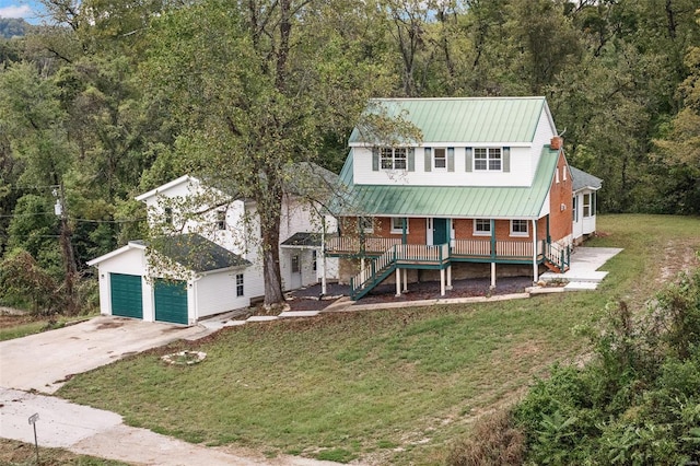 view of front facade with a front yard, a garage, a porch, and an outbuilding