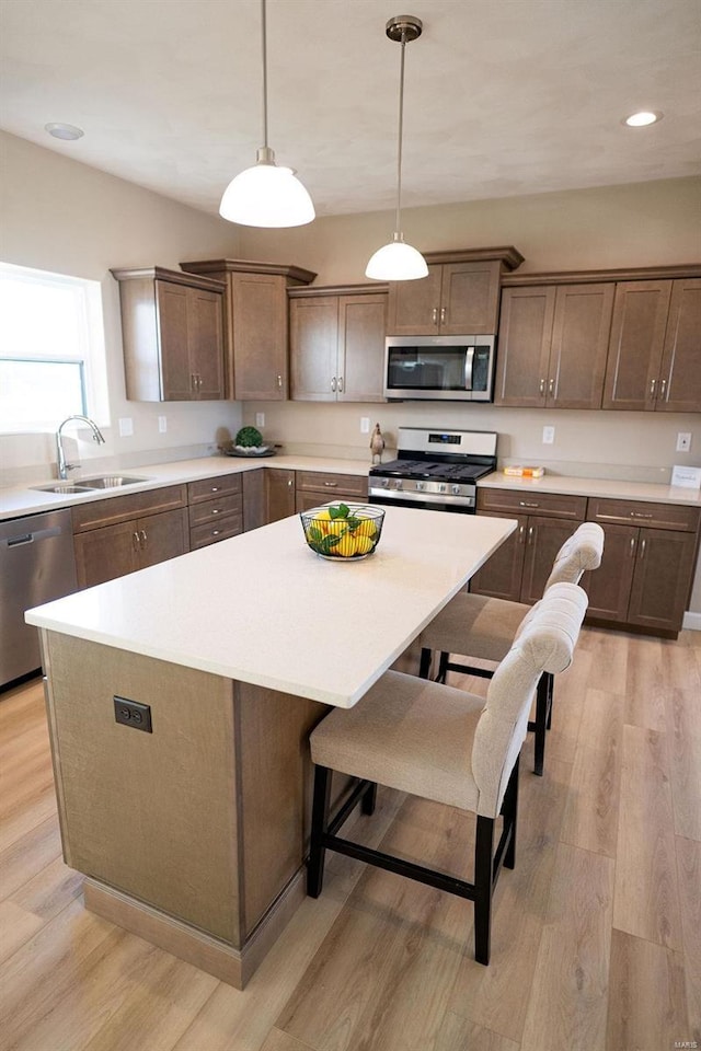 kitchen with pendant lighting, sink, a kitchen island, and stainless steel appliances