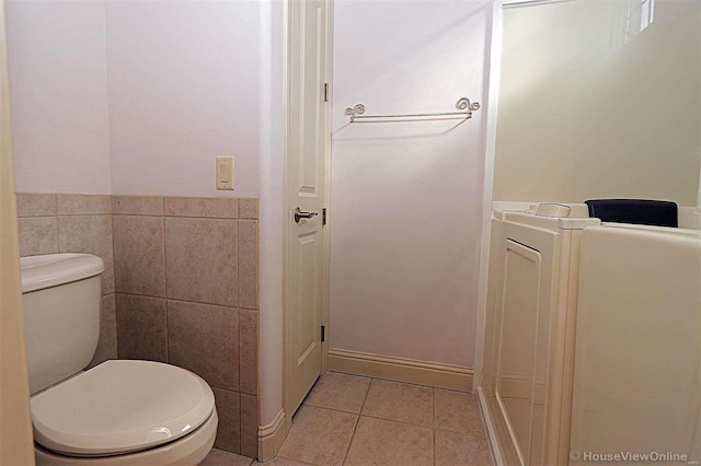 bathroom with toilet, tile walls, and tile patterned flooring