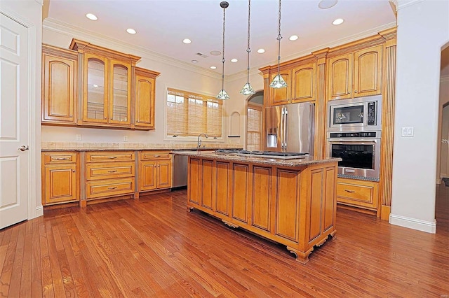 kitchen with a kitchen island, wood-type flooring, crown molding, pendant lighting, and appliances with stainless steel finishes