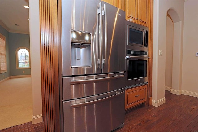 kitchen featuring decorative columns, stainless steel appliances, ornamental molding, and dark hardwood / wood-style floors