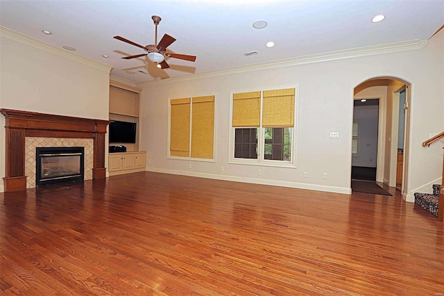 unfurnished living room featuring crown molding, a tiled fireplace, hardwood / wood-style flooring, and ceiling fan