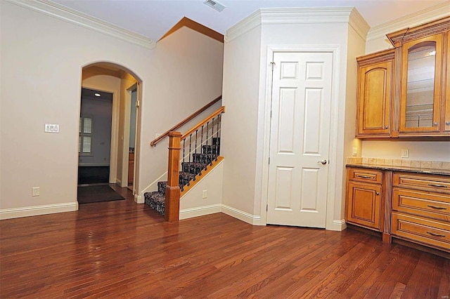 interior space featuring stone counters, ornamental molding, and dark hardwood / wood-style flooring