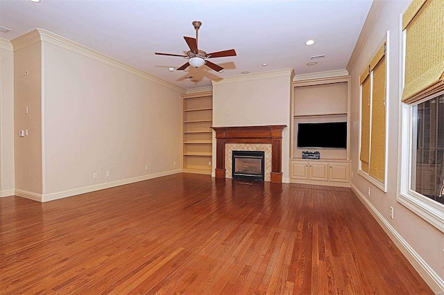 unfurnished living room with ceiling fan, wood-type flooring, ornamental molding, and a tile fireplace