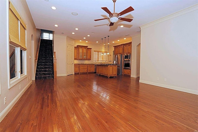 unfurnished living room with sink, ceiling fan, ornamental molding, and dark hardwood / wood-style flooring