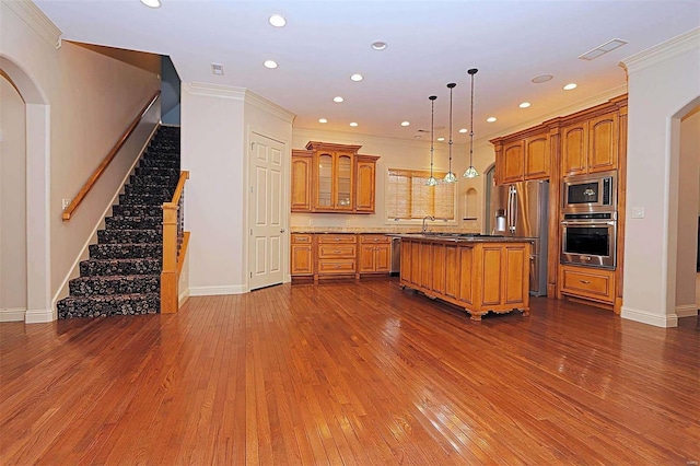 kitchen featuring dark wood-type flooring, stainless steel appliances, pendant lighting, and a kitchen island