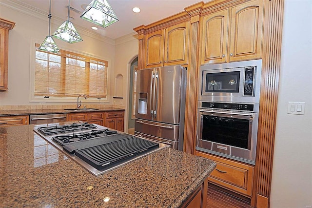 kitchen with ornamental molding, dark stone countertops, sink, decorative light fixtures, and stainless steel appliances