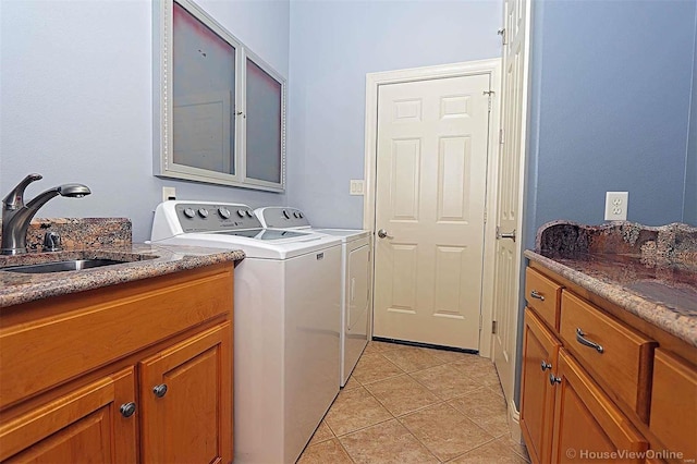 clothes washing area featuring cabinets, sink, washing machine and dryer, and light tile patterned floors