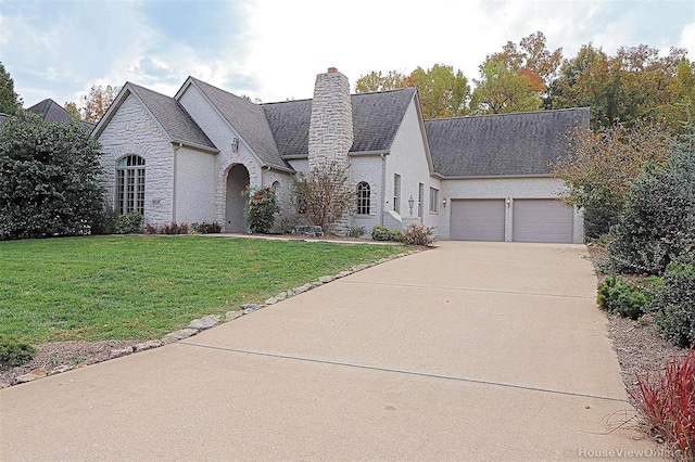 french country home featuring a front lawn and a garage