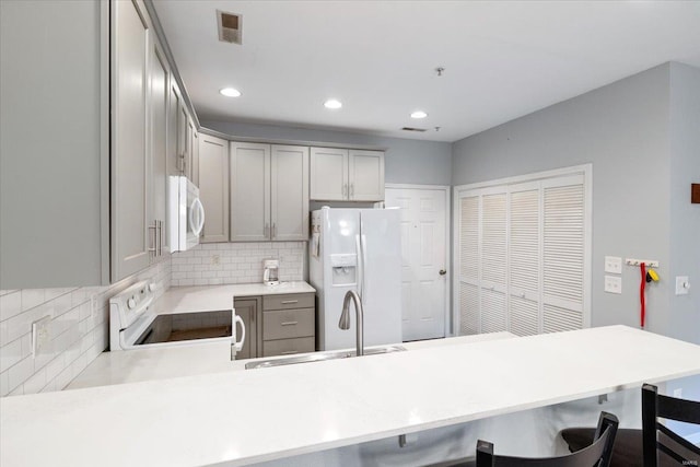 kitchen featuring white appliances, kitchen peninsula, sink, and a breakfast bar area