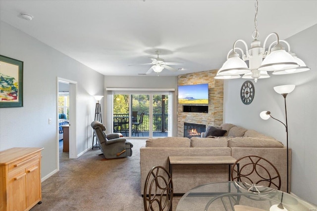 living room with a stone fireplace, ceiling fan with notable chandelier, and carpet flooring