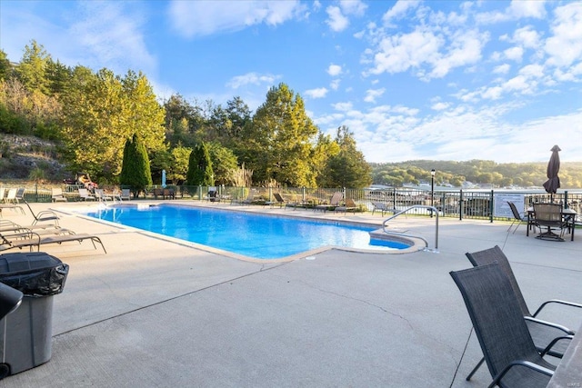 view of swimming pool featuring a water view and a patio