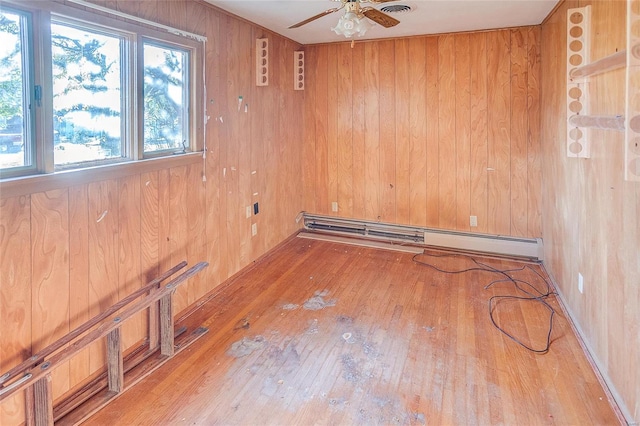 empty room featuring wood-type flooring, a wealth of natural light, and wooden walls