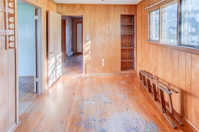 unfurnished room featuring wood walls, hardwood / wood-style floors, and built in features