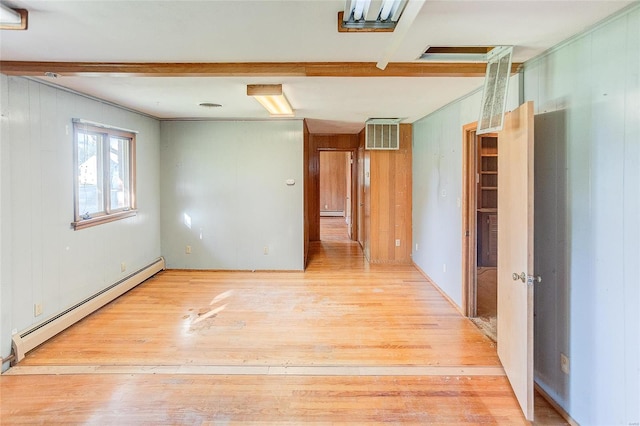 unfurnished room featuring light wood-type flooring, wood walls, and a baseboard radiator