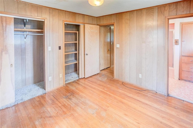 unfurnished bedroom featuring light wood-type flooring and wooden walls