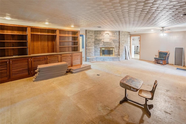 unfurnished living room featuring ceiling fan and a stone fireplace