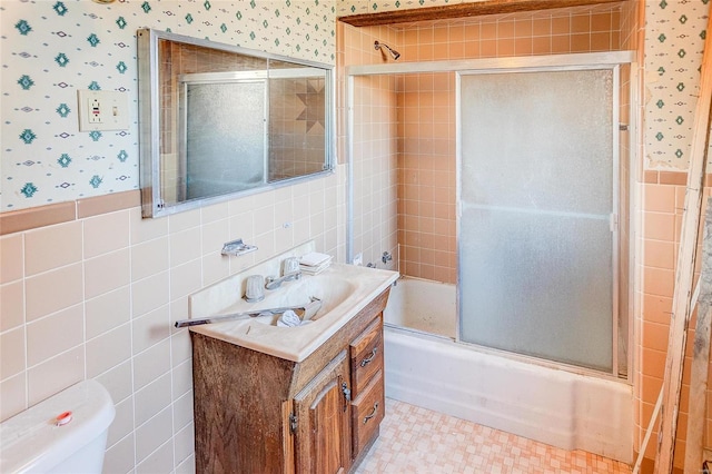 full bathroom featuring tile walls, toilet, vanity, and combined bath / shower with glass door