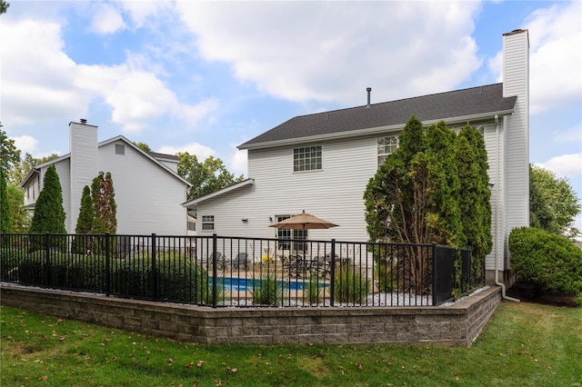 back of property featuring a covered pool and a lawn