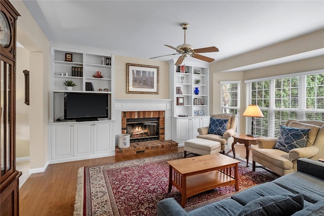 living room with built in features, plenty of natural light, light hardwood / wood-style floors, and a brick fireplace