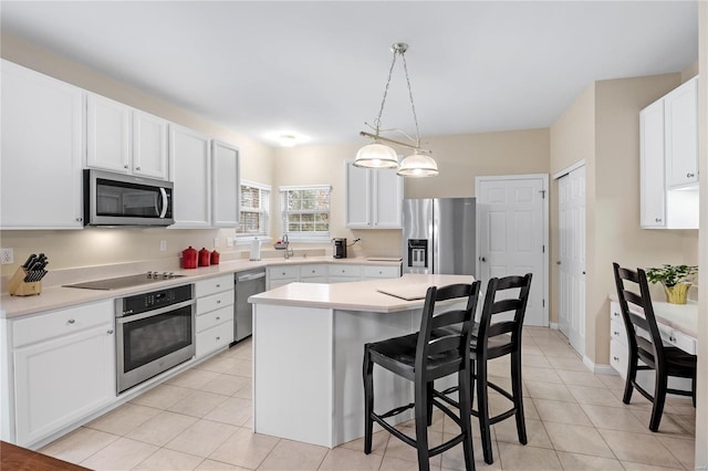 kitchen featuring pendant lighting, stainless steel appliances, a center island, white cabinets, and a kitchen bar