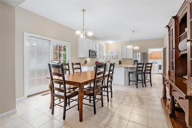 tiled dining area with a chandelier and washing machine and clothes dryer