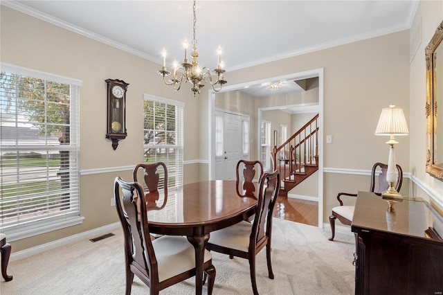 carpeted dining room featuring crown molding and a chandelier