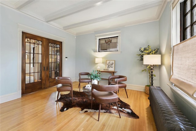 living area with plenty of natural light, light hardwood / wood-style flooring, beamed ceiling, and french doors