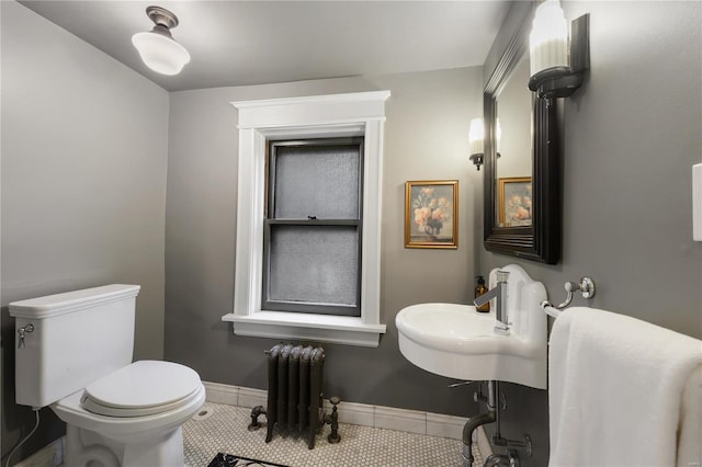 bathroom with tile patterned flooring, toilet, sink, and radiator