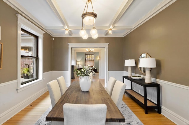 dining room with ornamental molding, coffered ceiling, beam ceiling, an inviting chandelier, and light hardwood / wood-style flooring