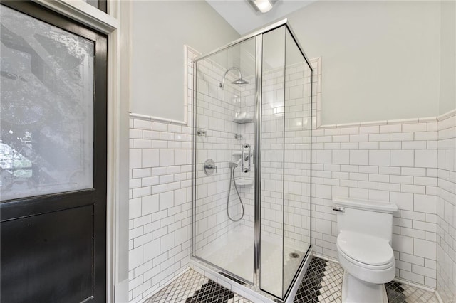 bathroom with tile patterned flooring, toilet, tile walls, and walk in shower