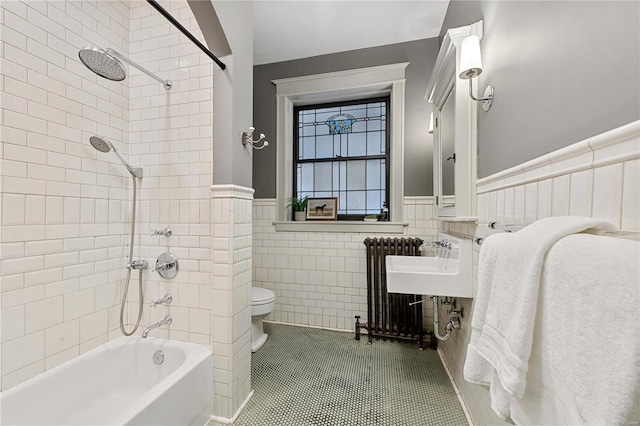 bathroom with toilet, tile patterned floors, radiator, and tile walls