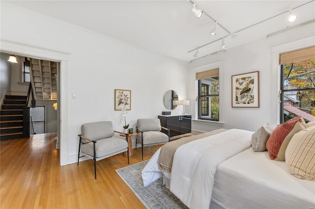 bedroom with track lighting and light hardwood / wood-style flooring