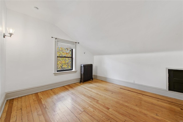 bonus room with light wood-type flooring, radiator, and vaulted ceiling