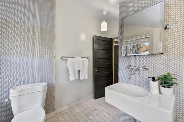 bathroom featuring toilet and tile walls