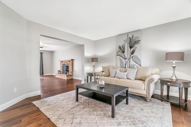 living room featuring a brick fireplace and wood-type flooring