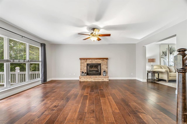 unfurnished living room featuring a brick fireplace, ceiling fan, and dark wood-type flooring