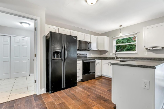 kitchen featuring sink, white cabinets, black appliances, decorative light fixtures, and dark hardwood / wood-style flooring