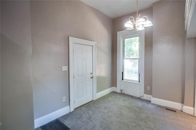 carpeted empty room featuring an inviting chandelier