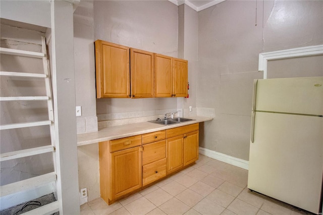 kitchen with light tile patterned floors, white refrigerator, and sink