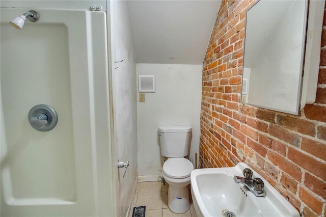 bathroom featuring toilet, sink, tile patterned floors, and brick wall