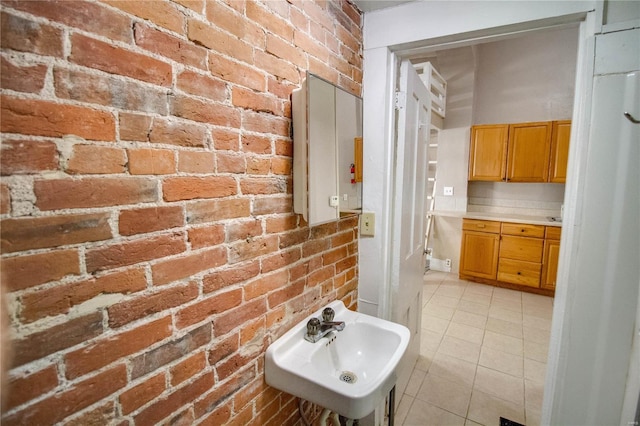 bathroom featuring brick wall, sink, and tile patterned floors